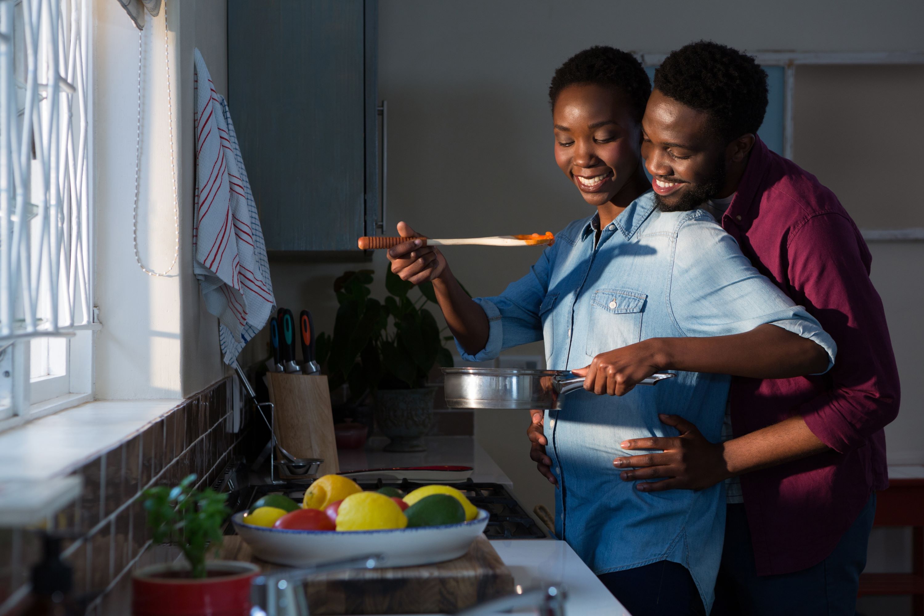 FEMME enceinte qui cuisine avec son conjoint